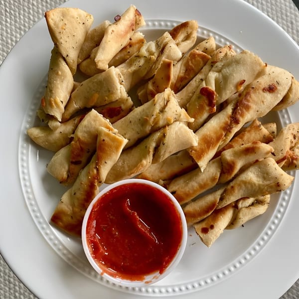 Mama Mimi's twisted breadsticks seasoned with herbs and cheese, served with a side of marinara sauce.