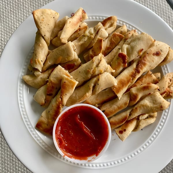 Mama Mimi's Take 'N Bake Pizza's twisted breadsticks, seasoned with herbs, served with a side of marinara sauce.